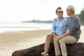 Asian Lifestyle senior couple hug and sitting on the beach happy in love romantic and relax time. Royalty Free Stock Photo